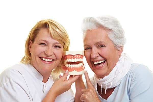 Clearwater dentist showing dentures model with senior patient smiling