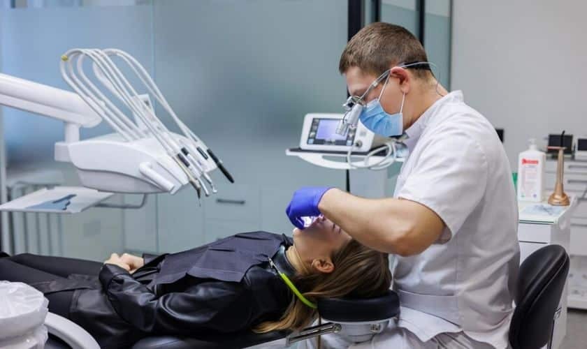 Dentist performing a procedure on a patient under nitrous oxide sedation with a nasal mask in a modern dental clinic.